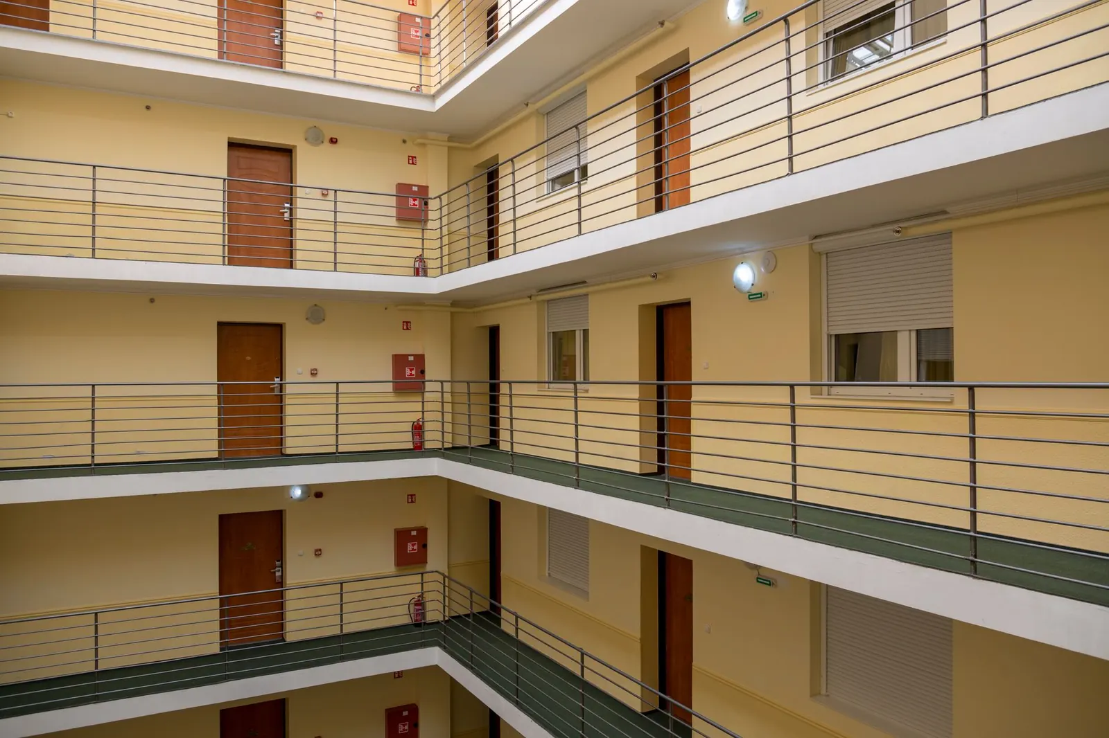 Interior view of a multi-story apartment building with metal railings and wooden doors.