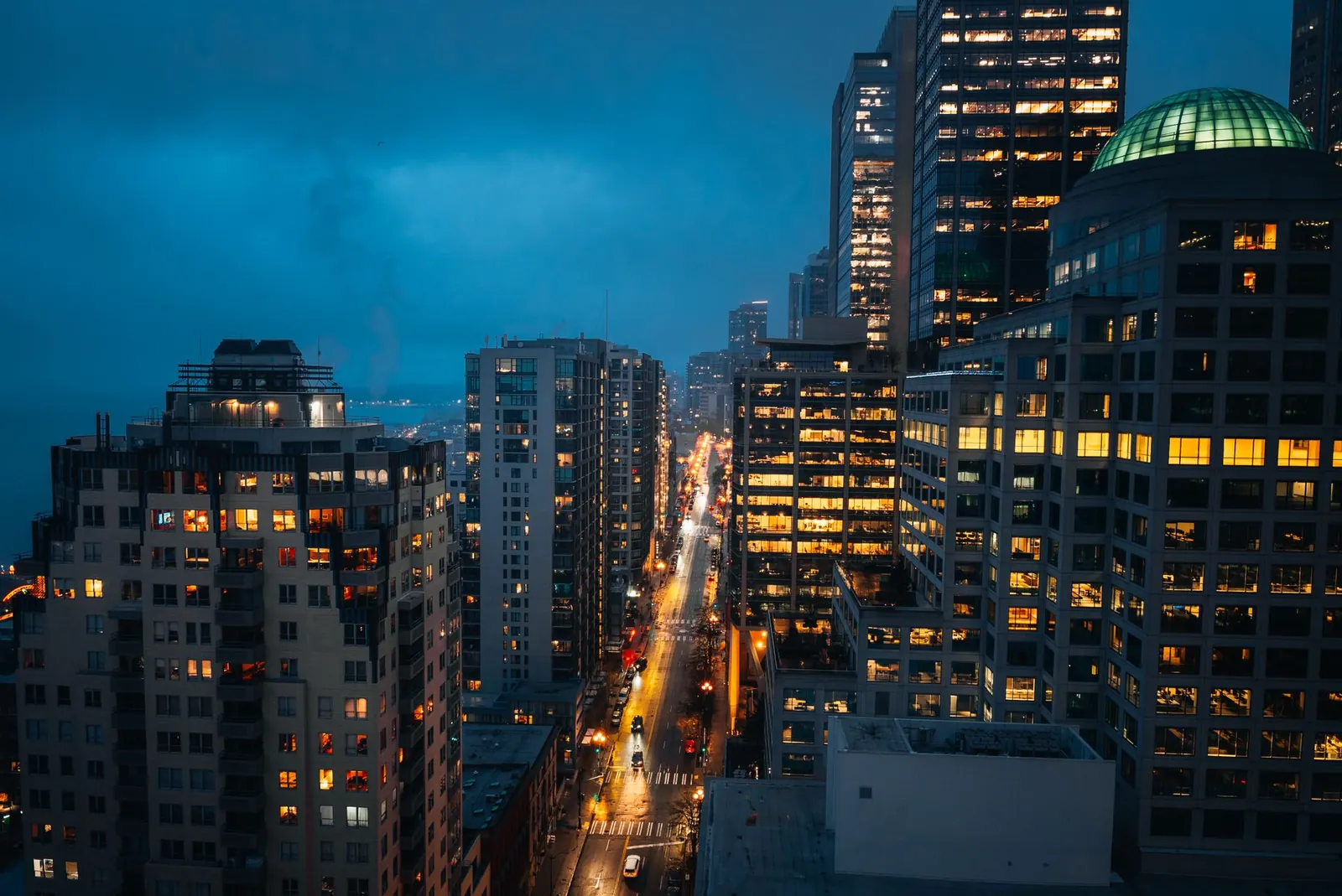 Atmospheric cityscape of downtown Seattle at night with vibrant streetlights and skyscrapers.